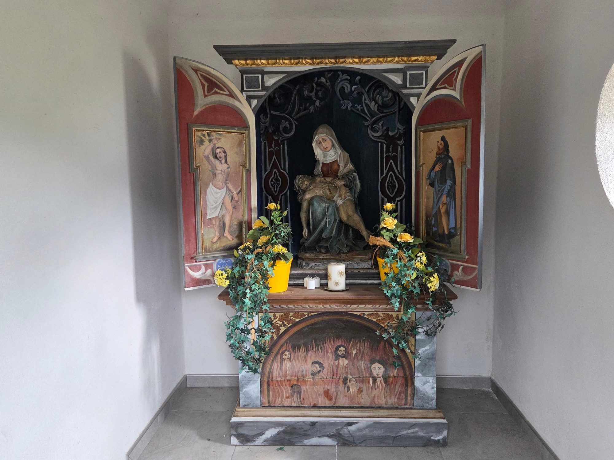 Der Altar mit einer Pieta im Zentrum und den Pestheiligen Sebastian und Rochus auf den Flügeln