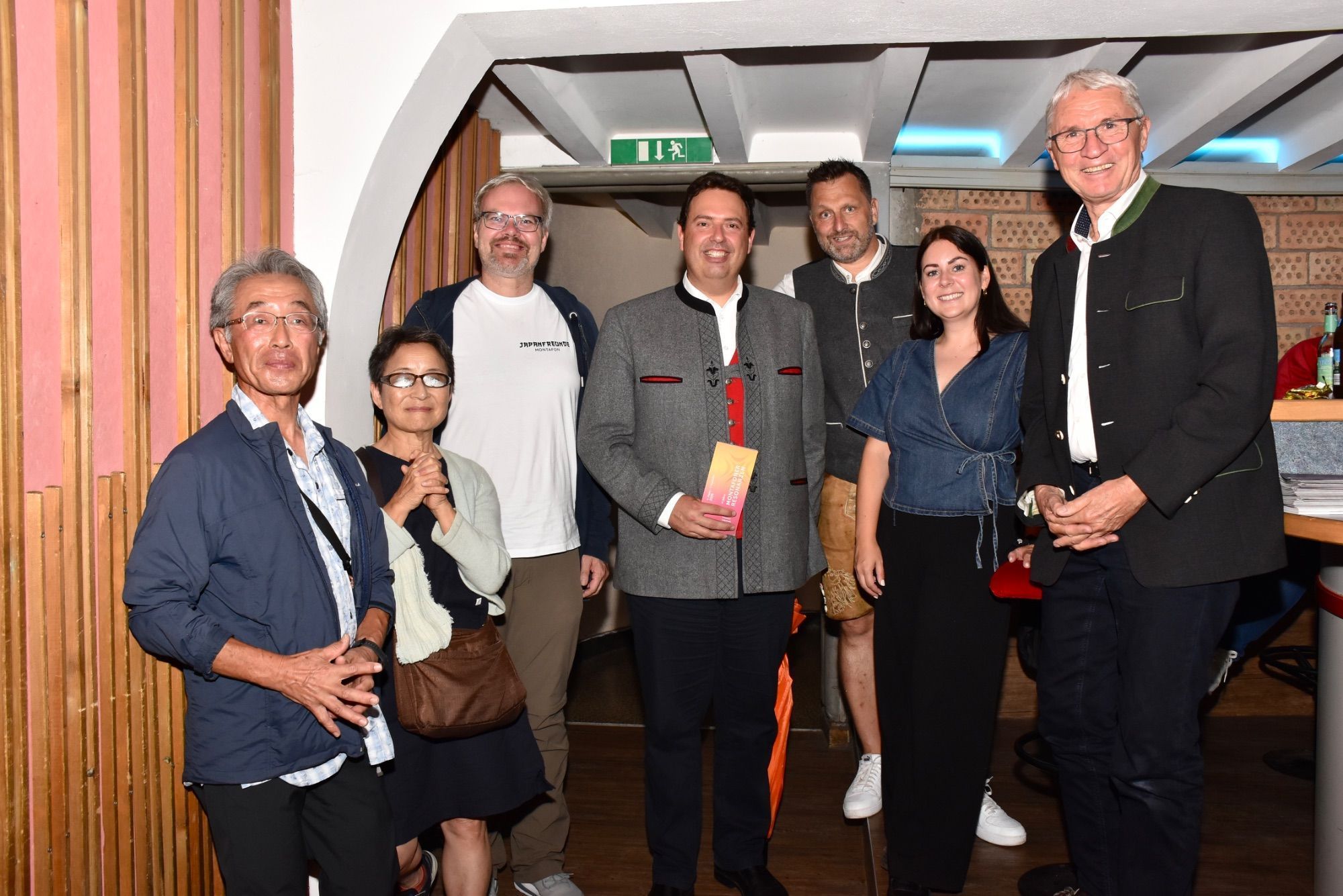 Ein Paar aus Japan, Andreas Brugger (Montafoner-Museen-Archivar), Dir. Manuel Bitschnau (Montafon Tourismus), Moderator Markus Barthold, Hannah Fritsche (Montafon Tourismus) und Hotelier Markus Felbermayer (Montafoner-Resonanzen-Kurator) in der Kulturbühne, Batloggstraße, Schruns, anlässlich der Montafoner Volksmusiktage.