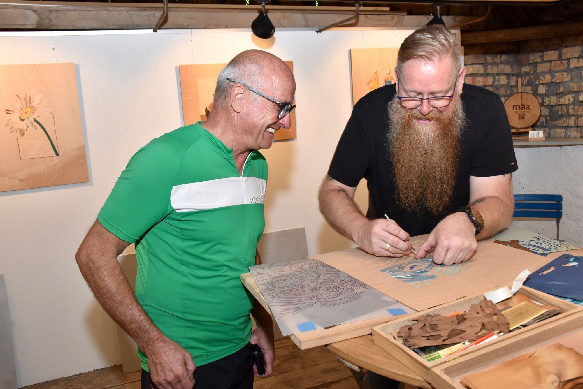 Gut beschildert war das Offene Sommeratelier im Betriebsgebiet Hängender Stein 4 in Ludesch. Die kleine Kunstoase lud zum Verweilen ein. Helmut Obexer schaute Markus Khüny interessiert über die Schultern. Daniel und Tiffany holten im Sommeratelier die beim Künstler in Auftrag gegebene Intarsienarbeit mit dem Wappen ihrer Familie - zufälligerweise auch Khüny - ab.