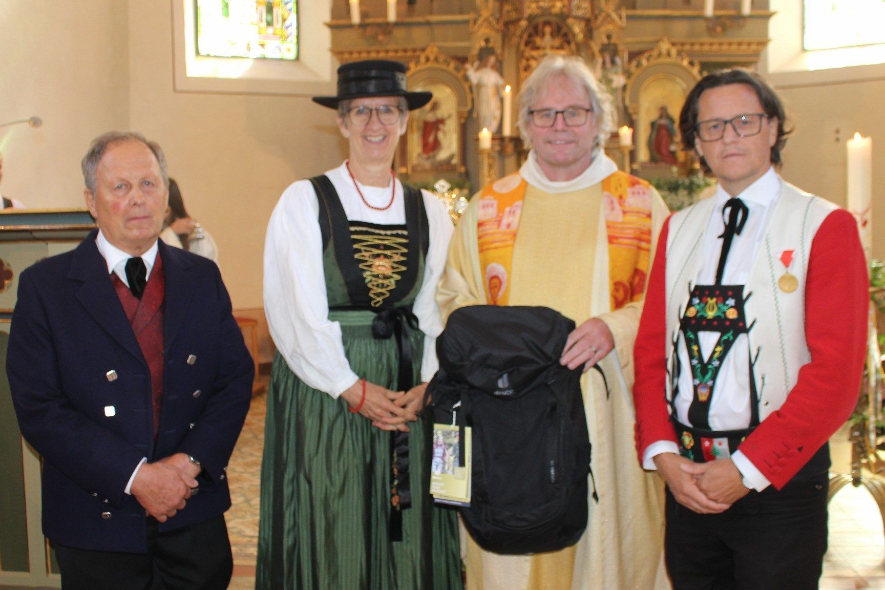 Heinz Feuerstein (l.), Steffi und Bürgermeister Stephan Schwarzmann überreichten sinnvolle Einstandsgeschenke: einen Rucksack für Bergtouren im Sommer und einen Gutschein für einen Satz Winterreifen, damit Friedel im Winter sicher nach Schröcken kommt.