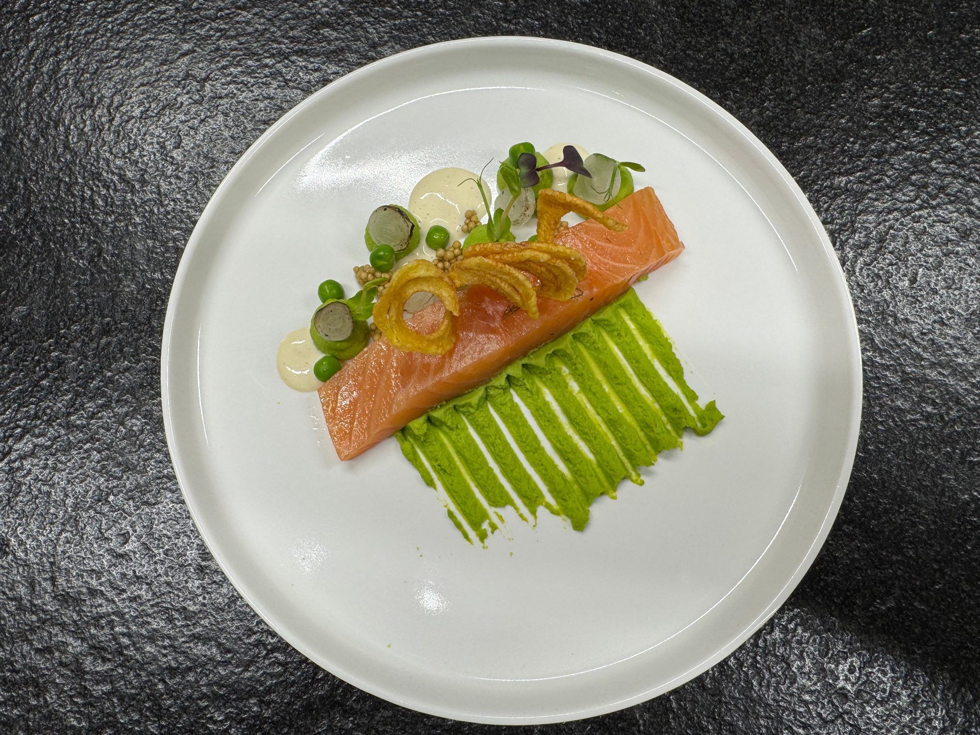 Hausgebeizter Gewürzlachs mit Erbsencreme, frittierten Kartoffeln und Perlzwiebeln.
