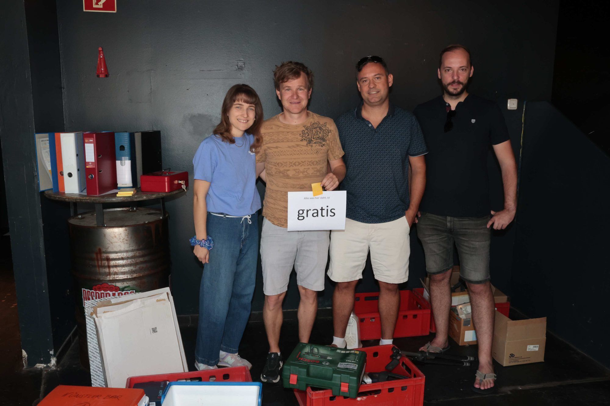 Johanna, Thomas, Thomas und Alex im Eingangsbereich vor gratis abzugebenden Aktenordnern.