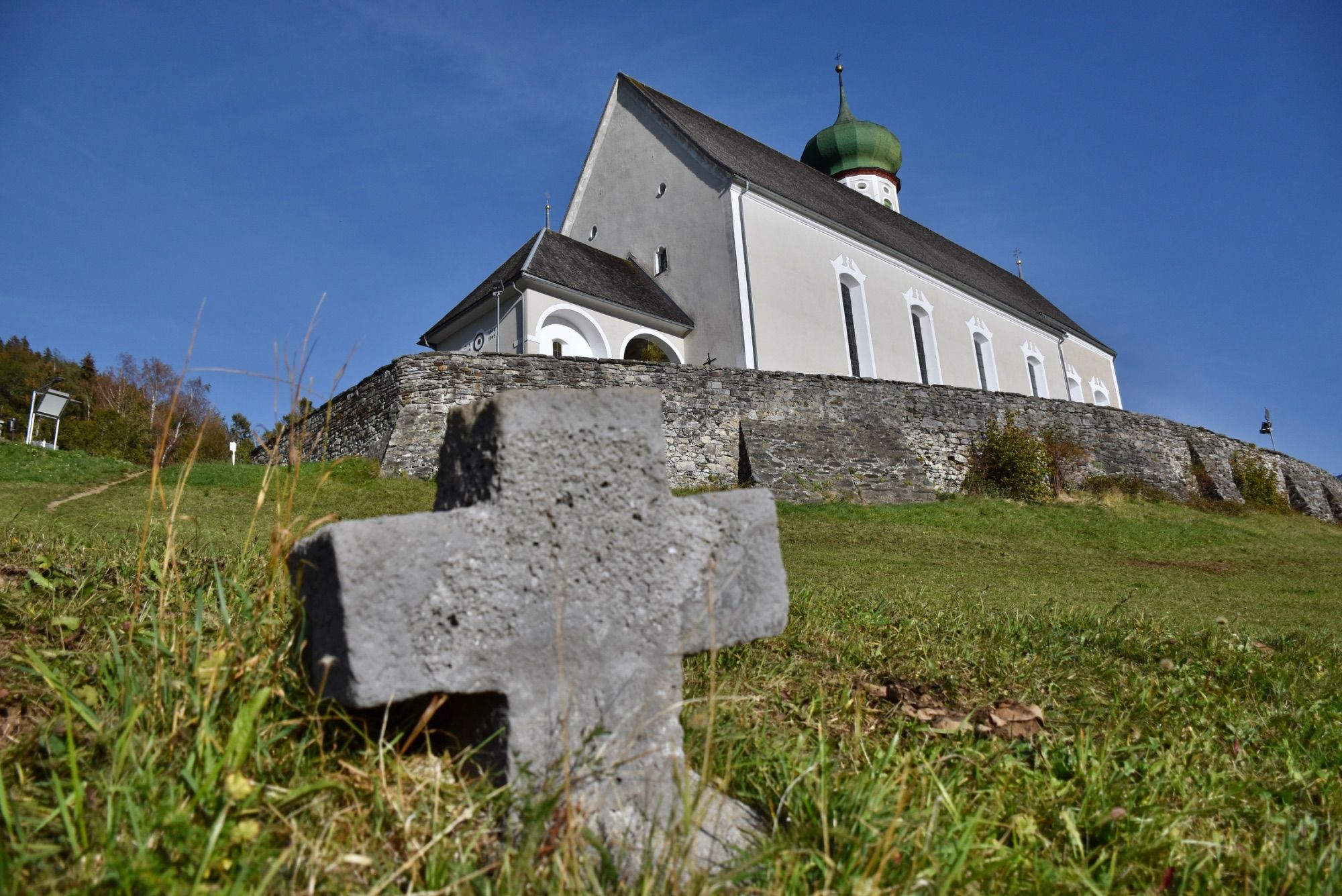 Die barocke Pfarrkirche Bartholomäberg liegt auf rund 1100 Metern Seehöhe. Das Steinkreuz befindet sich an dem schmalen Pfad, der von der Platta kommend vorbei am alten Gasthof Adler zum barocken Sakralbauwerk führt. Eine Tafel in Straßennähe informiert über das Steinkreuz; es handelt sich hierbei um ein besonderes Kulturdenkmal, so die Goethe-Universität Frankfurt.