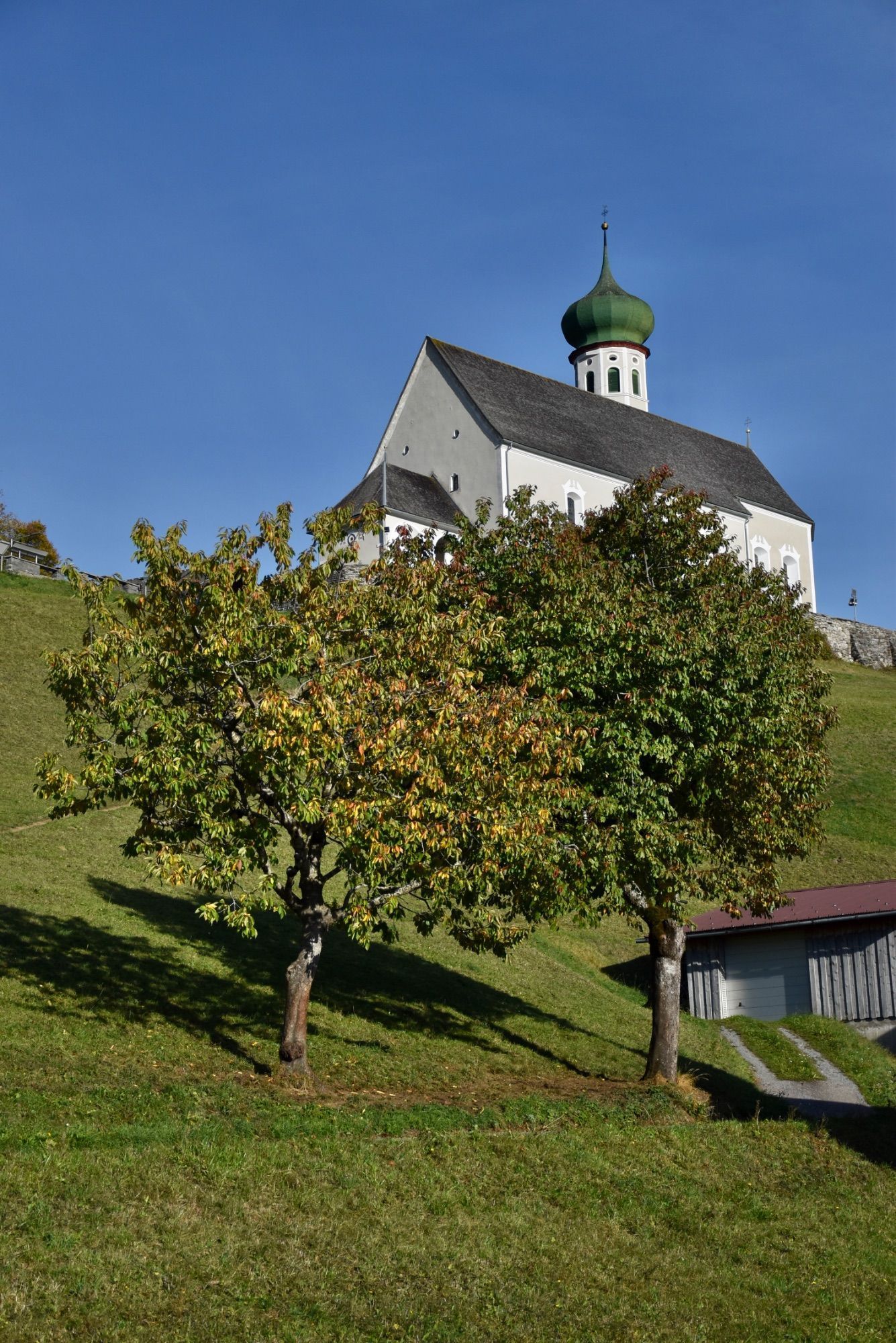 Die barocke Pfarrkirche Bartholomäberg liegt auf rund 1100 Metern Seehöhe. Das Steinkreuz befindet sich an dem schmalen Pfad, der von der Platta kommend vorbei am alten Gasthof Adler zum barocken Sakralbauwerk führt. Eine Tafel in Straßennähe informiert über das Steinkreuz; es handelt sich hierbei um ein besonderes Kulturdenkmal, so die Goethe-Universität Frankfurt.