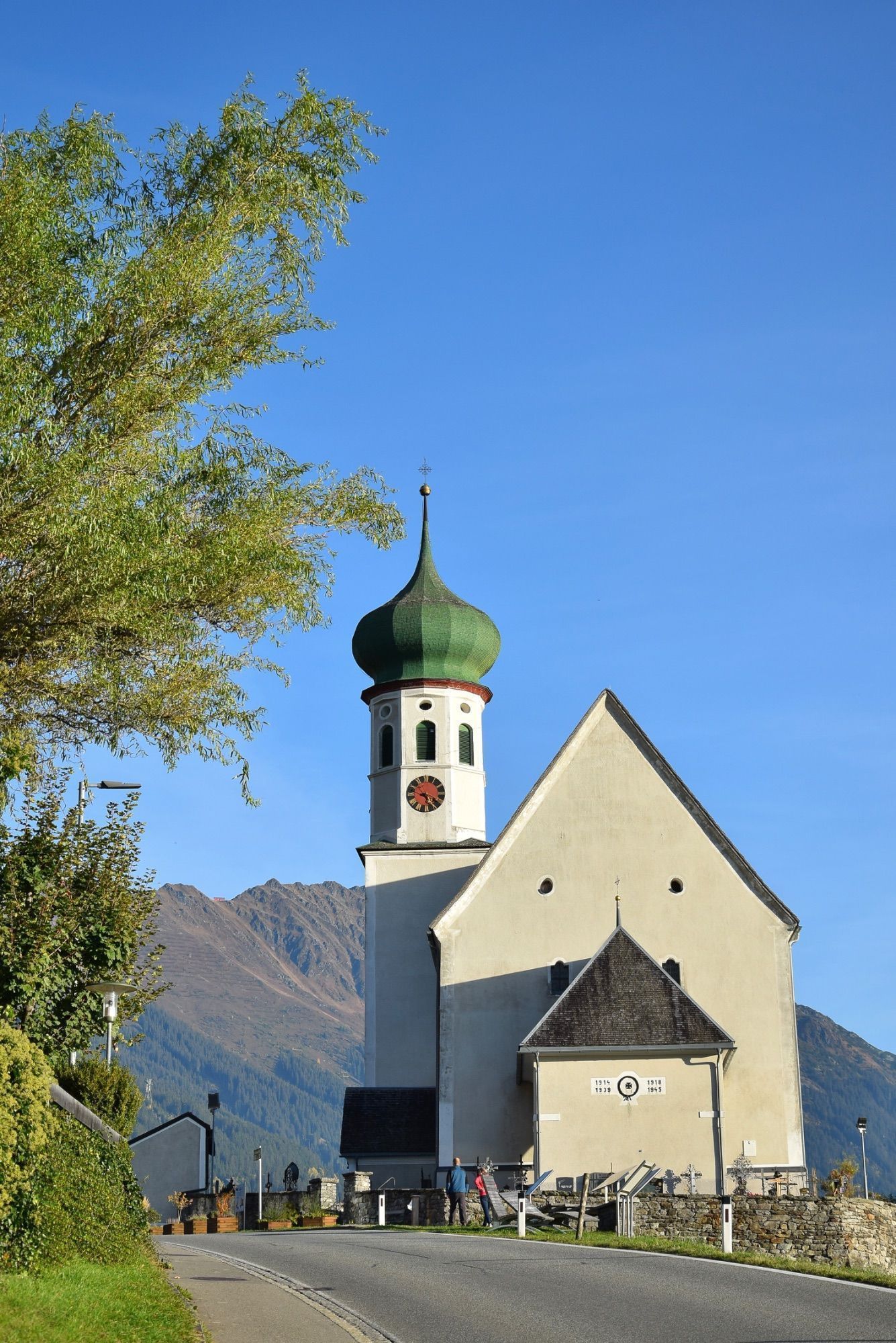 Die barocke Pfarrkirche Bartholomäberg liegt auf rund 1100 Metern Seehöhe. Das Steinkreuz befindet sich an dem schmalen Pfad, der von der Platta kommend vorbei am alten Gasthof Adler zum barocken Sakralbauwerk führt. Eine Tafel in Straßennähe informiert über das Steinkreuz; es handelt sich hierbei um ein besonderes Kulturdenkmal, so die Goethe-Universität Frankfurt.