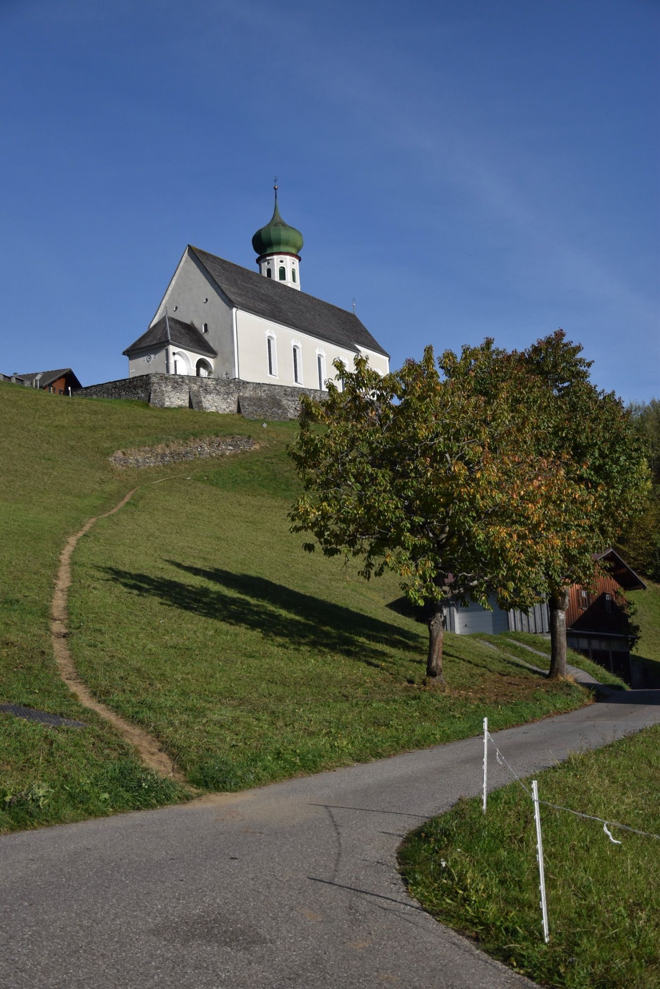 Die barocke Pfarrkirche Bartholomäberg liegt auf rund 1100 Metern Seehöhe. Das Steinkreuz befindet sich an dem schmalen Pfad, der von der Platta kommend vorbei am alten Gasthof Adler zum barocken Sakralbauwerk führt. Eine Tafel in Straßennähe informiert über das Steinkreuz; es handelt sich hierbei um ein besonderes Kulturdenkmal, so die Goethe-Universität Frankfurt.